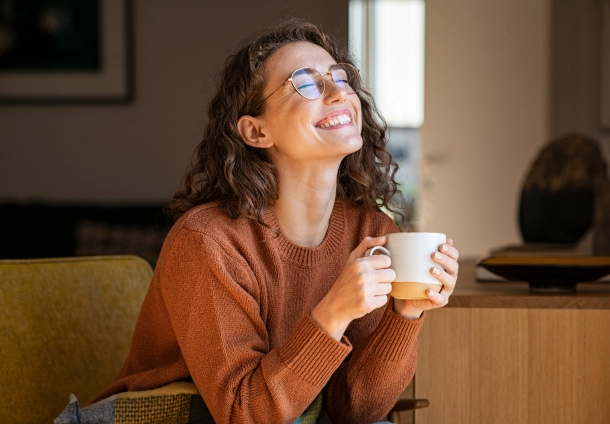 Photo of a curly haired girl holding a cup happy