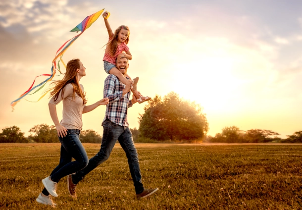 Photo of a father, mother and a child running with a kite