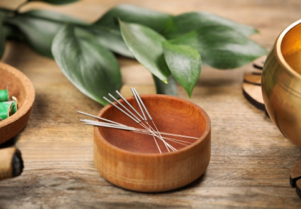 Photo of a wooden table with acupunture needles on a wooden bowl