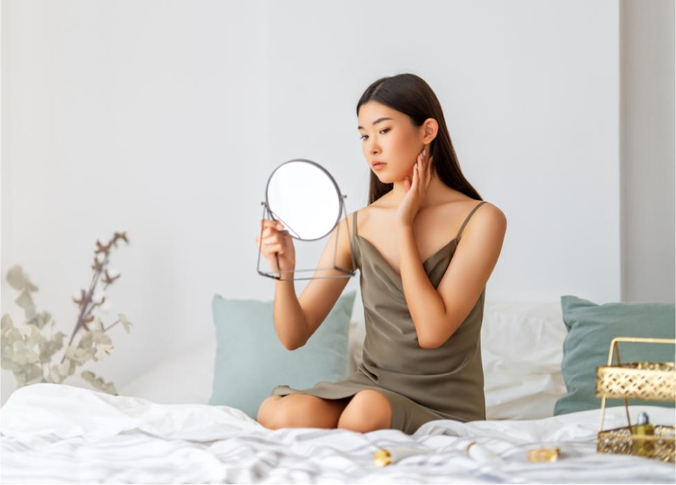 Portrait of attractive young woman looking at mirror. Beautiful girl enjoying her reflection, self-care concept.